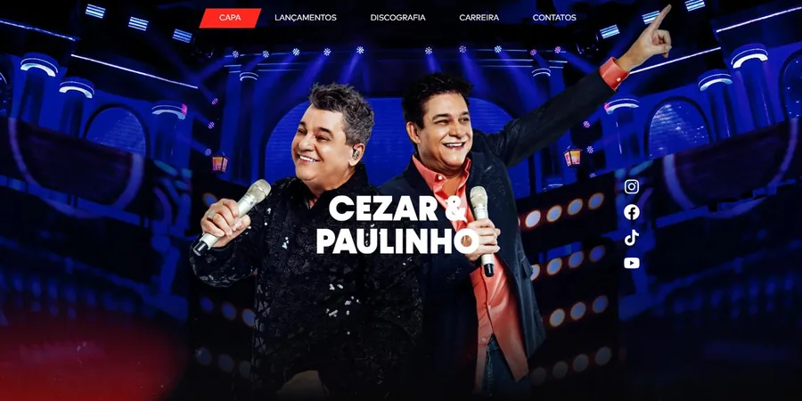 Capa do site oficial de Cezar e Paulinho, com a dupla cantando ao vivo sob luz azul de palco